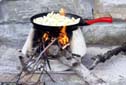 Potatoes being fried in olive oil on a traditional hearth